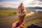 Enjoying local delight, hand holds ice cream against stunning Icelandic scenery