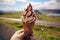 Enjoying local delight, hand holds ice cream against stunning Icelandic scenery