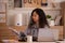 Enjoying the moment. At work, an Asian designer sits on a desk with his laptop, tablet, and documents, looking well and pleased