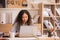 Enjoying the moment. At work, an Asian designer sits on a desk with his laptop, tablet, and documents, looking well and pleased