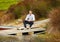 Enjoying some rest and relaxation. Portrait of a mature wine maker sitting on a jetty with a glass of red wine.