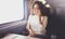 Enjoying travel concept. Young pretty woman tourist traveling by the train sitting near the window using smartphone.