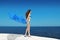 Enjoyment. Bikini model woman with blowing tissue over blue sky, outdoors. Brunette girl at seaside. Summertime.