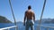 Enjoyment of freedom, young man with hands to side stands on stern of yacht and delight sea scenery