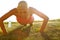 Ensuring that every muscle gets toned. A young woman doing push-ups in a field.