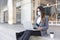 Enterprising young woman sitting on the street working from her laptop. She is wearing a face mask and formal clothes. Selective