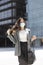 Enterprising young woman walking resolutely between office buildings. She wears a medical mask as a preventive measure for the