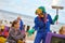 Entertainer in blue overalls and beast mask scaring little girl, outdoor costume festival at beach