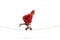 Entertainer in a red suit riding a small bike over a tightrope