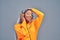 Enthusiastic afro american woman listening favorite music by earphones and dancing over grey background