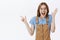 Enthusiastic excited and thrilled emotive caucasian woman in glasses and brown overalls raising hand in surprise and joy