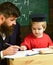 Enthusiastic kid studying with teacher. Father checking homework, helps to boy, son. Teacher in formal wear and pupil in