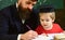 Enthusiastic kid studying with teacher. Homeschooling concept. Teacher in formal wear and pupil in mortarboard in