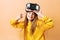 Enthusiastic little girl wearing virtual reality headset modern innovation device isolated on yellow