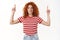 Enthusiastic motivated good-looking redhead female curly hair smiling white teeth wear striped t-shirt pointing up