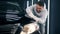 Enthusiastic serviceman is cleaning a car with a cloth