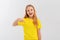 Enthusiastic teen girl smiling, pointing finger down, showing promo offer, way to store, banner or logo, standing in blank yellow