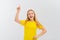 Enthusiastic teen girl smiling, pointing finger up, showing promo offer, way to store, banner or logo, standing in blank yellow