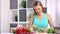 Enthusiastic young housewife chopping cucumber cooking vegetable salad in kitchen at home