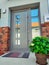 Entrance door to modern house with beautiful potted plants, bushes and green grass