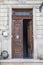 Entrance doorway in an ancient stone wall with stairs leading up.      the old metal wrought-iron door is locked with a padlock. C