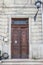 Entrance doorway in an ancient stone wall with stairs leading up.      the old metal wrought-iron door is locked with a padlock. C