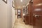 Entrance hall of a house with an armored access door, a long corridor with marble floors and reddish woodwork