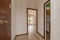 Entrance hall of a house with a reddish wooden door, terrazzo floors and white painted walls