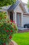 Entrance of a luxury house with a patio and beautiful landscaping on a sunny day. Garden in front of detached house