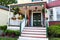 Entrance of old ornate gingerbread victorian style house decorated for summer with flowers and porch decor