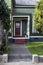 Entrance and porch to colorful victorian gingerbread house with trees - lace curtains in door window