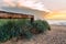 Entrance to the beach of the Baltic Sea along a wooden railing and tall grass, a sandy beach at sunset,