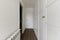 Entrance to a bedroom with a large custom wardrobe with white doors, white aluminum radiator and wooden floor