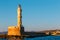 Entrance to Chania harbor with lighthouse at sunset, Crete, Greece