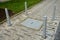 Entrance to the collector shaft bounded by metal posts on the sidewalk. the hatch must not be damaged so it is around the bollard