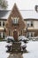 Entrance to cute upscale two story old English style brick and lattice home in falling snow