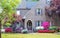 Entrance to grey brick two story house landscaped with Japanese Maples and Azaleas with shutters and a front seating area