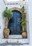 The entrance to the house is framed by two jugs of flowers.