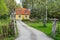 Entrance to the house. Two storey villa cottage colored in yellow. Wooden fence with gate around the village house. Trimmed green