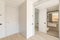 Entrance to the interior of modern apartment with white walls and wooden floor. View to the entrance door and bathroom