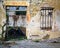 Entrance to an old French building with no door and no roof. With bars on the windows. Built of stone and bricks. Peeling plaster