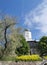 The entrance to the Vyborg Castle and the St. Olaf Tower, past the yellow flowers and trees in the city of Vyborg against the blue