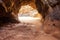 entrance to a winding cave with a sandy floor