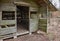 Entrance of a wooden hut in the forest with a sign with the German inscription