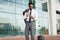 Entrepreneur Using Cellphone Standing With Suitcase At Airport Outdoor