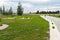 Entry for cars into the property made of openwork concrete pavement filled with colorful pebbles, around is green grass and small