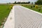 Entry for cars into the property made of openwork concrete pavement filled with colorful pebbles, around is green grass and small