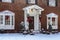 Entry and porch to traditional Georgian style brick house with columns and bay windows decorated for Christmas in the snow