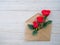 Envelope of Kraft paper, with flowers red roses on a wood background, space for text, as congratulation wedding