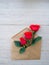 envelope of Kraft paper, with flowers red roses on a wood background, space for text, as congratulation wedding, birthday